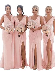 four bridesmaids in pink dresses posing for the camera with their bouquets on