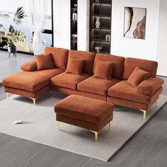 a living room with an orange sectional couch and footstool in front of a large window