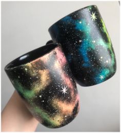 two handmade coffee mugs sitting on top of each other with stars painted on them