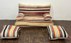 a multicolored striped chair and footstool with matching pillows on the floor