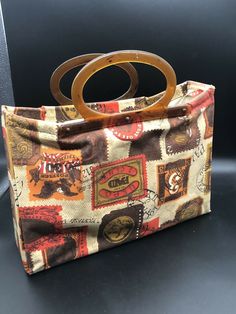 a handbag with a wooden handle is sitting on a black surface and it has many different pictures all over it