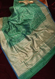 Step into the world of timeless elegance with this Authentic Banarasi Pure Dupion Silk Saree in a majestic Green hue, adorned with a delicate Floral Zari Border.  The Dupion silk is a matt textured drape and features a deep antique tone zari and features a dotted pattern of florals jaal, that showcases the exceptional artistry and expertise of Banarasi weavers. This adds depth and dimension to the saree's design, with each motif meticulously crafted to embody the essence of traditional Indian cr Green Jamawar Pre-draped Saree For Festivals, Traditional Green Pre-draped Saree With Zari Weaving, Transitional Green Pre-draped Saree With Zari Weaving, Green Pre-draped Saree With Zari Weaving For Transitional Season, Festive Green Jamawar Pre-draped Saree, Transitional Jamawar Saree With Zari Weaving, Green Jamawar Pre-draped Saree With Zari Weaving, Green Jamawar Pre-draped Saree With Zari Work, Transitional Self-design Banarasi Silk Pre-draped Saree