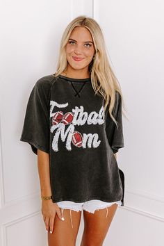 - Sparkle on the sidelines with this adorable 'FOOTBALL MOM' top! Perfect for showing your team spirit, this piece is comfy-casual style with a touch of glam. Its eye-catching design makes it a must-have for every proud football mom. - Unlined sweatshirt material with a vintage wash - A white and red hued 'FOOTBALL MOM' graphic design with rhinestone accents - Unfinished seam accents - A crew cut neckline - Short, loose sleeves - An ultra-relaxed silhouette that ends in a high-low hemline with s Game Day Black Tops With Team Name, Black Tops With Team Name For Game Day, Varsity Style Top With Embroidered Graphics For Fan Gear, Sporty Washed Black Top For Fall, Black Varsity T-shirt For Fall, Black Tops For Baseball Game Day, Black Varsity Top For Game Day, Casual Tops For Game Day During Football Season, Black Tops For Game Day