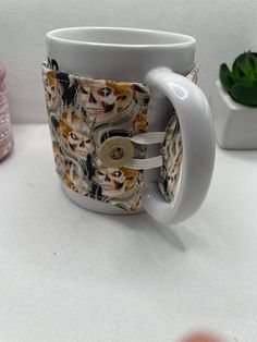 a white coffee mug with skulls on it sitting on a table next to other items