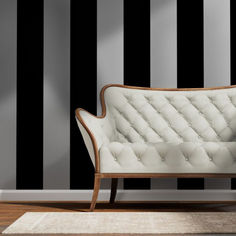 a white couch sitting on top of a wooden floor next to a black and white striped wall