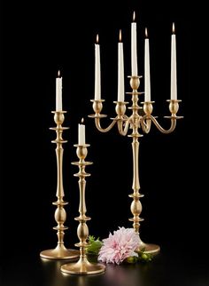 a group of candles sitting on top of a table next to a pink flower and a candle holder