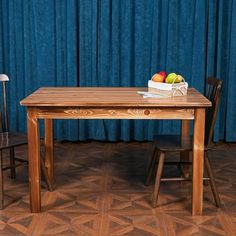 a wooden table and two chairs in front of a blue curtain with fruit on it