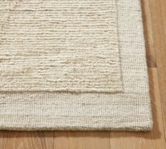 a white rug on top of a wooden floor next to a wood flooring board