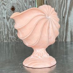 a pink vase sitting on top of a table next to a wooden wall and door