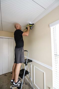 a man is painting the ceiling in his home