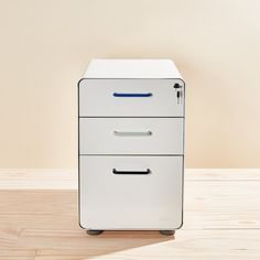 a white filing cabinet sitting on top of a wooden floor