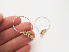 "* Pair of Olive leaf earrings. * Gold-tone leaves with Silver ear-wire. * 1.3\" Drop. To see these earrings in SILVER: https://www.etsy.com/listing/268833213/silver-leaf-earrings-silver-hoop The olive branch has been a worldwide symbol of peace since ancient times. These peaceful earrings feature a cascade of detailed brass olive leaves dangling from the end of a sterling silver hoop. The ear-wire is standard gauge for all regular ear piercings. Thread the ear-wire through your piercing and let Silver Leaf-shaped Brass Earrings, Leaf-shaped Brass Earrings With Ear Wire, Leaf Earrings Silver, Statement Piece Jewelry, Boho Items, Branch Earrings, Eco Friendly Jewelry, Olive Leaf, Olive Branch