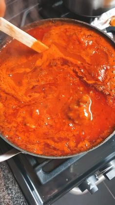 a pan filled with meatballs and sauce on top of an oven burner next to other cooking utensils