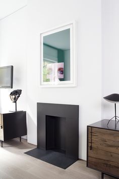 a living room with a fireplace, television and mirror on the wall in it's corner