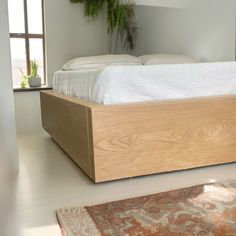 a bed with a wooden headboard sitting on top of a white floor next to a rug