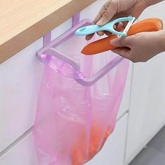 a person holding a pair of scissors over a plastic bag with carrots in it