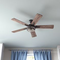 a ceiling fan in a room with blue curtains