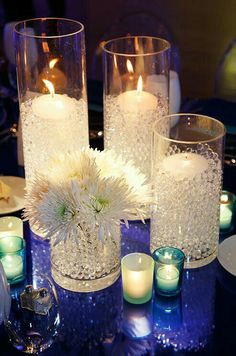 candles and flowers on a table with glass vases