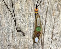 a wooden necklace with two glass beads and a bead on the end is sitting on a piece of wood