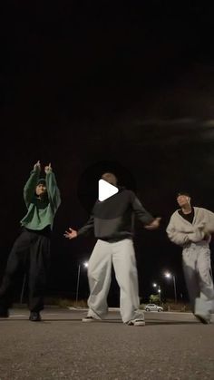 three men are dancing in the street at night