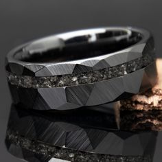 two wedding bands made out of black diamonds on top of each other, with one diamond embedded in the middle