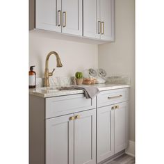 a kitchen with white cabinets and gold faucet pulls on the cabinet doors, next to a sink