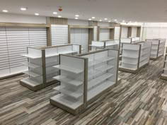 an empty store with shelves and shelvings in the middle, on wooden flooring