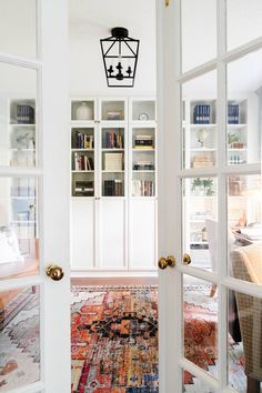 an open door leading to a living room with a rug on the floor and bookshelves in the background