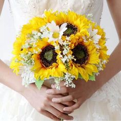 a bride holding a bouquet of sunflowers and daffodils in her hands