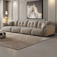 a living room with a couch, coffee table and horse painting on the wall behind it