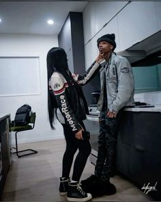 a man and woman standing next to each other in an office setting, talking on their cell phones