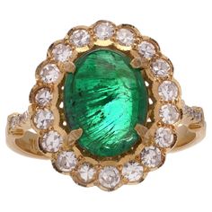 Zambian Cabochon Emerald and Diamond 18kt Gold Cluster Ring. Elevate your style with this stunning Zambian Emerald and Diamond Cluster Ring, a masterpiece of elegance and sophistication. Crafted from exquisite 18kt yellow and white gold, this ring features a dazzling oval faceted Zambian emerald as its centrepiece. Surrounding the emerald are 26 round brilliant-cut diamonds. Specifications: Finger Size: UK: N EU: 55 US: 7 Ring Dimensions: 2.7 x 2 x 1.7 cm Weight: 6.00 grams Emerald Details: Origin: Zambia Cut: Oval faceted Quantity: 1 Total Carat Weight: 4.63 carats Treatment: Natural Diamond Details: Cut: Round Brilliant Quantity: 26 Total Carat Weight: 0.90 carats Colour: F - G Clarity: SI1 Condition: The ring is pre - owned, excellent condition overall. Zambian Emerald, Diamond Cluster Ring, Zambia, Diamond Cluster, Emerald Diamond, Round Brilliant Cut Diamond, Cluster Ring, Round Brilliant, Natural Diamonds