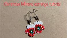 a pair of christmas mittens earrings with bead work on them sitting on a table