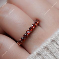 a woman's hand with a ring made out of red and orange stones on it