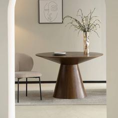 a vase with flowers sitting on top of a wooden table next to a white chair