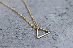 A 16K gold plated triangle, hangs on a delicate 16K gold plated chain, making a simple but elegant statement. The perfect layering piece or minimalist necklace.  The triangle measures half of an inch (14mm) and you decide the length of the chain. If you would like a chain length not offered, simply write it in the notes at the time of purchase. Add a 2" extender chain to give you flexibility in length! Ex. If you choose a 16" chain, you would be able to wear the necklace any length from 16"- 18" Elegant Gold Triangle Necklace, Minimalist Gold Triangle Jewelry, Minimalist Triangle Gold Jewelry, Minimalist Triangle Brass Jewelry, Dainty Gold Triangle Jewelry, Minimalist Geometric Necklaces For Everyday, Gold Geometric Minimalist Necklace, Minimalist Gold Geometric Necklace, Minimalist Geometric Gold Necklace