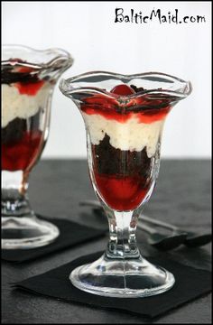 two dessert dishes with red and white toppings in glass bowls on a black table