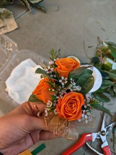 someone is holding a bouquet of flowers in front of some scissors and other things on the table