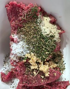 raw meat with herbs and seasoning in a white bowl