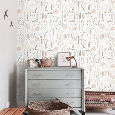 a room with a dresser, basket and wallpaper