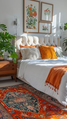 a bed with orange and white pillows on top of it next to a rug in front of a window