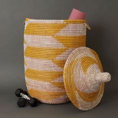 Large size storage basket with hooded lid in yellow and white pattern. Measures approx. 17" diameter, 23" without hood, and 30" height with hood. For storing laundry, toys or 8 throw blankets Woven from grass and recycled plastic ribbons using traditional coil weaving technique. Handmade by Wolof tribe women in Senegal, Africa. --------------------- The Wolof people in Senegal are known for weaving colorful baskets from locally harvested cattail stalks and strips of plastic. They weave handmade Large Basket With Lid, Hooded Lids, Small Storage Basket, Colorful Baskets, Wine Bottle Topper, Grass Basket, Mirror With Hooks, Large Storage Baskets, Handmade Baskets