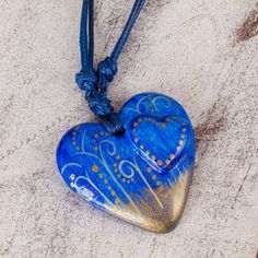 A heart as blue as the ocean comes to life in papier mache. Hand-painted motifs suggest the movement of the wind. Resplendent with golden accents the pendant centers a delightful necklace by Edith Orozco. A coat of lacquer protects it and adds shine. Hand Painted Blue Spiritual Necklace, Blue Heart-shaped Keepsake Jewelry, Blue Heart-shaped Spiritual Necklace, Blue Heart Pendant Keepsake Jewelry, Spiritual Blue Heart Pendant Necklace, Unique Blue Heart-shaped Necklace, Unique Blue Heart Pendant Necklace, Unique Blue Jewelry For Valentine's Day, Unique Blue Keepsake Necklace