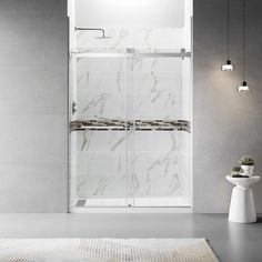 a bathroom with a white rug and marble tile shower walls, along with two lights on the side of the bathtub