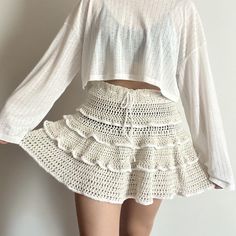 a woman is wearing a white top and crochet skirt with her hands on her hips