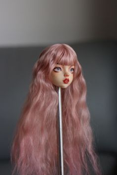 a doll with long pink hair holding a stick