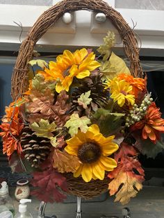 a wicker basket filled with sunflowers, leaves and pineconis sitting on top of a counter