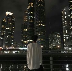 a man standing on the edge of a bridge looking at some tall buildings in the distance