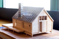 a model house sitting on top of a piece of wood in front of a window