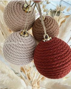 three balls of yarn are hanging from a tree ornament with gold bells on them